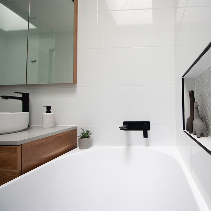 (FP) IMG_5919-700x700 White tiled bathroom with bathtub and black fixtures