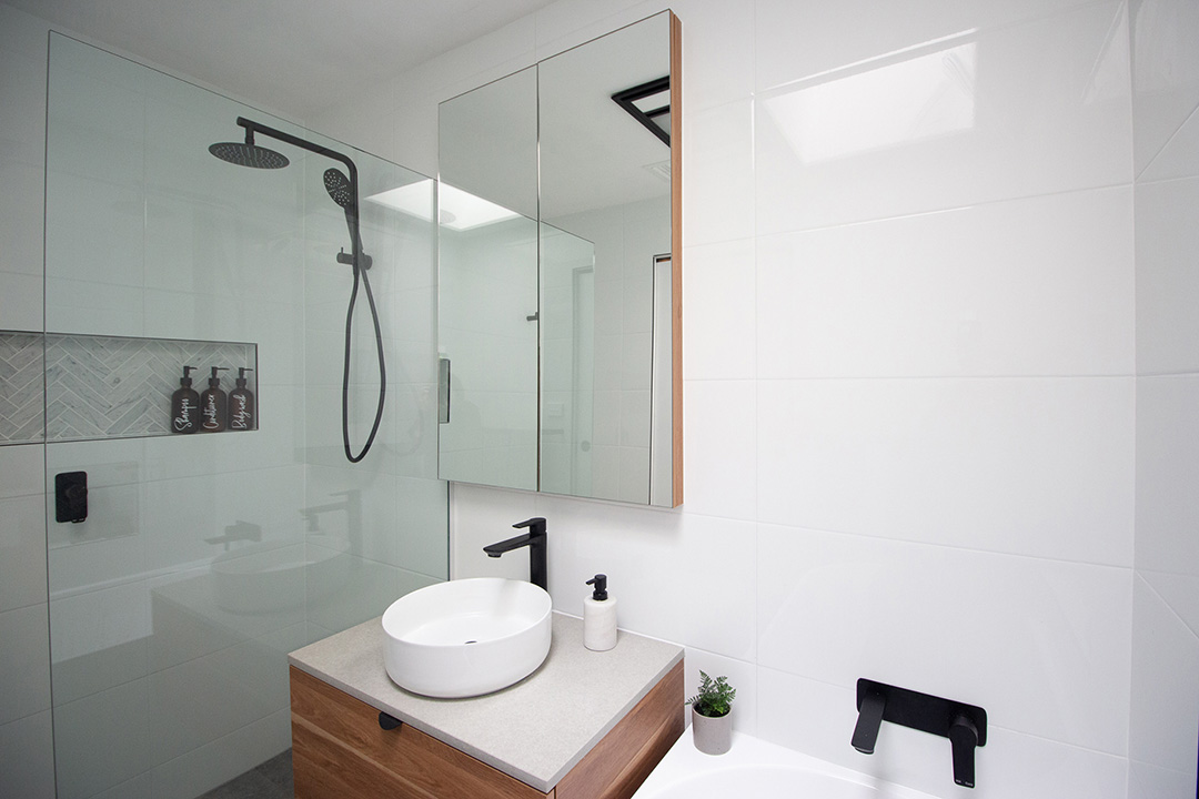 IMG_5918-1080 White tiled bathroom with black faucets and handles.